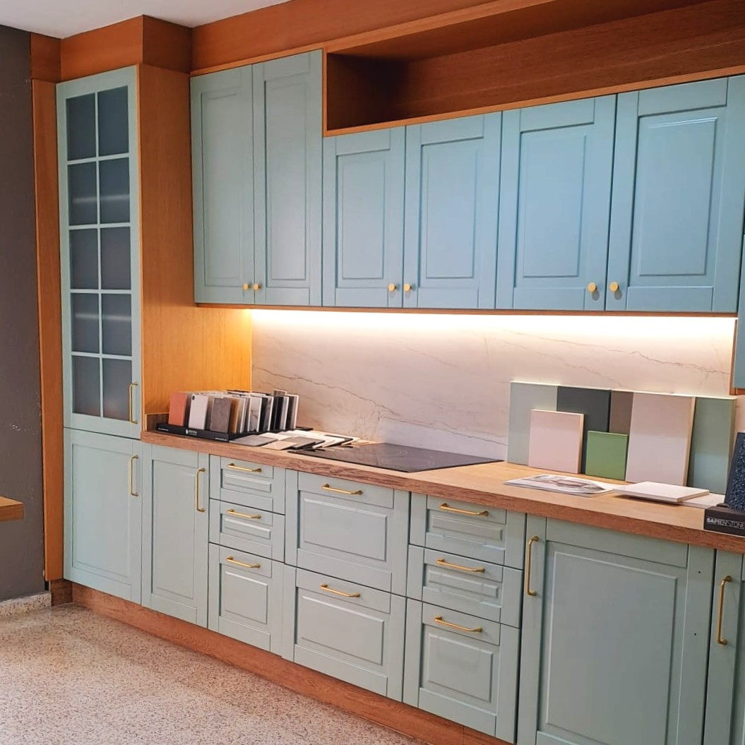 Exposición de cocina en tienda con muebles verde salvia y encimera de mármol